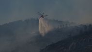 A helicopter sprays water above a wild fire at mount Parnitha, in Parnitha near Athens, on June 29, 2024. (Photo by Aris Messinis / AFP)