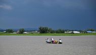 People wade through flood waters on a boat at Lehpati village of Morigaon district in India's northeastern state of Assam on July 3, 2024. (Photo by Biju Boro / AFP)