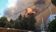 Bystanders flee as a wildfire burns next to a hospital near Patras on July 9, 2024.  (Photo by Eurokinissi / AFP) 
