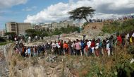 People stand on the edge of a dumpsite where six bodies were found at the landfill in Mukuru slum, Nairobi, on July 12, 2024. Kenyan police have announced the opening of an investigation after the discovery of six bodies in a landfill in the capital Nairobi on Friday. (Photo by SIMON MAINA / AFP)
