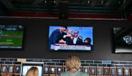 People inside the Fiserv Forum watch the news on television after hearing that Donald Trump was evacuated from the stage of his rally in Pennsylvania on July 13, 2024 in Milwaukee, Wisconsin. (Photo by Angela Weiss / AFP)