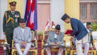 Nepal's newly appointed prime minister Khadga Prasad Sharma Oli (C) signs a document as his predecessor Pushpa Kamal Dahal looks on at the presidential house in Kathmandu on July 15, 2024. (Photo by Prabin Ranabhat / AFP)