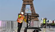 A worker stands on the Trocadero with the Eiffel Tower, bearing the olympics rings, seen in the background ahead of the Paris 2024 Olympic and Paralympic games, in Paris on July 19, 2024. (Photo by Manan Vatsyayana / AFP)
