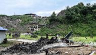 Rescuers and officials stand at the crash site after a Saurya Airlines' plane crashed during takeoff at the Tribhuvan International Airport in Kathmandu on July 24, 2024.  (Photo by Prakash Mathema / AFP)