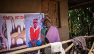 A woman leans against a commemorative poster of a family member perished during a nearby landslide in Kencho Shacha Gozdi on July 25, 2024. (Photo by Michele Spatari / AFP)
