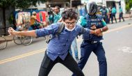 A Bangladesh police personnel detains a student during a rally against quotas in government jobs, along the street in Dhaka on July 29, 2024. (Photo by Abu Sufian Jewel / AFP)