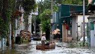 This photo taken on July 28, 2024 shows a man rowing a boat through flood waters in Ben Voi village on the outskirts of Hanoi. Photo by Nhac NGUYEN / AFP