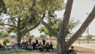 People sit in the shade at Mosqueda Park in Fresno, California as temperatures soar into the triple digits. (Photo by Philip Cheung for The Washington Post)


