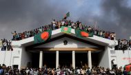 Anti-government protestors display Bangladesh's national flag as they storm Prime Minister Sheikh Hasina's palace in Dhaka on August 5, 2024. Bangladesh army chief Waker-Uz-Zaman spent nearly four decades rising to the top of the military and said on August 5, he was 