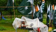 A vendor looks on as he sells PAKISTAN national flags along a street, amid rainfall in Islamabad on August 7, 2024, ahead of the country's independence day. (Photo by Aamir QURESHI / AFP)