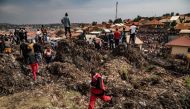 A Red Cross officer runs for help following a landfill collapse in Kampala on August 10, 2024. Eight people including two children were killed when mountains of garbage collapsed at a landfill in the Ugandan capital Kampala on August 10, the city authority said. (Photo by BADRU KATUMBA / AFP)
