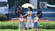 A woman uses an umbrella as she walks along the Mirae Scientists Street in Pyongyang during high temperatures on August 13, 2024. (Photo by KIM Won Jin / AFP)
