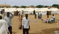 Sudanese already displaced by conflict, walk near tents at a makeshift campsite they were evacuated to following deadly floods in the eastern city of Kassala on August 12, 2024. (Photo by AFP)
