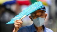 A man uses his fan to shade himself from the sun in Seoul on August 16, 2024, during a prolonged heatwave which has gripped much of the country. (Photo by ANTHONY WALLACE / AFP)