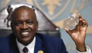 Botswana's President Mokgweetsi Masisi holds a large diamond discovered in Botswana at his office in Gaborone on August 22, 2024. (Photo by Monirul Bhuiyan / AFP)

