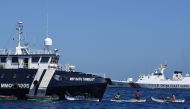 File: This photo taken on February 15, 2024 shows Filipino fishermen aboard their wooden boats, as a Chinese coast guard ship monitors near the China-controlled Scarborough Shoal, in disputed waters of the South China Sea. (Photo by Ted Aljibe / AFP)

