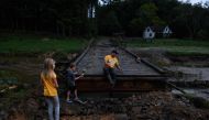 A man and his kids take a break from working on a washed out road to their home in Watauga County, North Carolina on September 27, 2024. (Photo by Melissa Sue Gerrits / GETTY IMAGES NORTH AMERICA / Getty Images via AFP)
