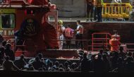 A captain of Spanish Salvamento Maritimo (Sea Search and Rescue agency) scorts one of the 17 minors (C) who arrived in a group of 133 migrants at La Restinga port, after being rescued by the Spanish Salvamento Maritimo Salvamar Adhara vessel off the coast of the Canary island of El Hierro, prior to being transferred to the San Andres Temporary Reception Center for Foreigners. (Photo by Antonio SEMPERE / AFP)
