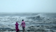 People stand ashore as they observe waves amidst heavy winds and rainfall at Marina Beach in Chennai on November 30, 2024, ahead of the landfall of cyclone Fengal in India's state of Tamil Nadu. (Photo by R. Satish BABU / AFP)
