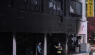 Firefighters and a police officer stand in front of a commercial building that was damaged by a fire that broke out at the Bundang district in Seongnam on January 3, 2025. (Photo by Philip FONG / AFP)
