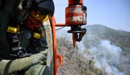 A Thai Department of Disaster Prevention and Mitigation (DDPM) personnel on a firefighting helicopter inspects fire spots to drop water to combat forest fires over Mae On district in the northern Thai province of Chiang Mai on March 26, 2025. Photo by MANAN VATSYAYANA / AFP