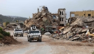 United Nations peacekeepers drive in vehicles of the UN Interim Force in Lebanon (UNIFIL) past destroyed buildings while patroling in Lebanon's southern village of Kfar Kila close to the border with Israel on April 6, 2025. (Photo by Rabih Daher / AFP)