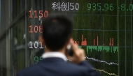 A man looks at a screen showing Chinese stock market movements as he uses his mobile phone in Beijing on April 7, 2025. (Photo by WANG Zhao / AFP)
