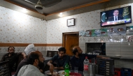 People watch a television in a restaurant as Pakistan's Prime Minister Shehbaz Sharif addresses the nation, in Islamabad on May 7, 2025. (Photo by Aamir Qureshi / AFP)