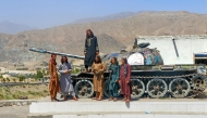 Taliban security personnel pose on a Soviet tank along a road in Surobi district, Kabul province on May 20, 2025. (Photo by MOHAMMAD FAISAL NAWEED / AFP)
