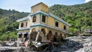 A man takes pictures of a damaged mosque, a day after flash floods in Balgran village near Muzaffarabad, capital of Pakistan-administered Kashmir on May 28, 2025. (Photo by Sajjad Qayyum / AFP)