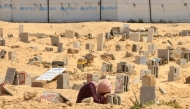 A Palestinian woman mourns over the grave of relative in Khan Yunis in the southern Gaza Strip on June 16, 2025.  (Photo by AFP)