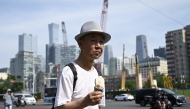 A man holding an ice cream crosses a street in Beijing on June 23, 2025. Photo by WANG Zhao / AFP.
