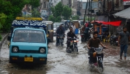 Commuters make their way through a flooded street following heavy rainfall in Hyderabad, in Sindh province on June 27, 2025. (Photo by Akram Shahid / AFP)
