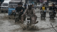 Commuters make their way through a flooded street after heavy rainfall in Karachi on June 28, 2025. (Photo by Rizwan Tabassum / AFP)

