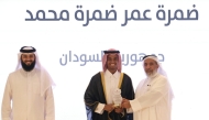 Minister of Awqaf and Islamic Affairs H E Ghanem bin Shaheen bin Ghanem Al Ghanim honouring a student at the graduation ceremony.