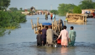 File photo for representational purposes only. Men walk along a flooded road with their belongings, following rains and floods during the monsoon season in Sohbatpur, Pakistan, August 28, 2022. (REUTERS/Amer Hussain)