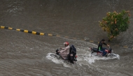 Commuters wade through a flooded street following heavy monsoon rains in Lahore on July 10, 2025. (Photo by Arif ALI / AFP)
