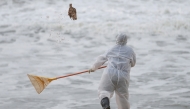 A Sri Lankan navy member throws a dead fish back to water while cleaning the debris washed to a beach from the MV X-Press Pearl container ship which caught fire and sank off the Colombo Harbour, in Ja-Ela, Sri Lanka June 14, 2021. REUTERS/Dinuka Liyanawat