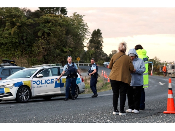 Police officers and locals stand near a roadblock where a police shootout occurred near the town of Piopio, located in New Zealand痴 Waikato region on September 8, 2025. Photo by DJ MILLS / AFP