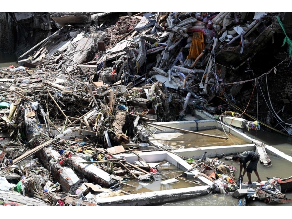 A man (R) walks on the rubble of a collapsed building after flooding in Denpasar on Indonesia's resort island of Bali on September 12, 2025. Photo by SONNY TUMBELAKA / AFP