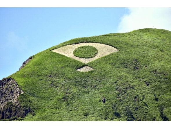 Grass mowed into the shape of a fan bearing the Japanese flag is seen on a mountain in Aso, Kumamoto Prefecture. Photo by The Japan News
