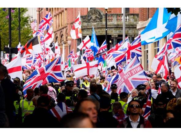 Supporters of British far-right activist Tommy Robinson whose real name is Stephen Yaxley-Lennon, walk through central London waving flags during a 'Free speech' march, on September 13, 2025. (Photo by CARLOS JASSO / AFP)