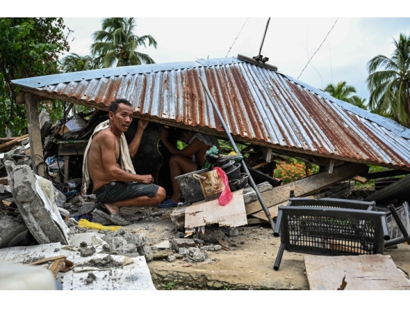 Men look for items in a collapsed house in Manay, in the province of Davao Oriental on October 11, 2025. (Photo by Jam Sta Rosa / AFP)
