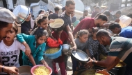 Displaced Palestinians gather to receive food portions outside the damaged Imam al Shafi'i Mosque, where families have taken shelter, in the Zeitoun neighbourhood of Gaza City on October 23, 2025. (Photo by Omar Al-Qattaa / AFP)