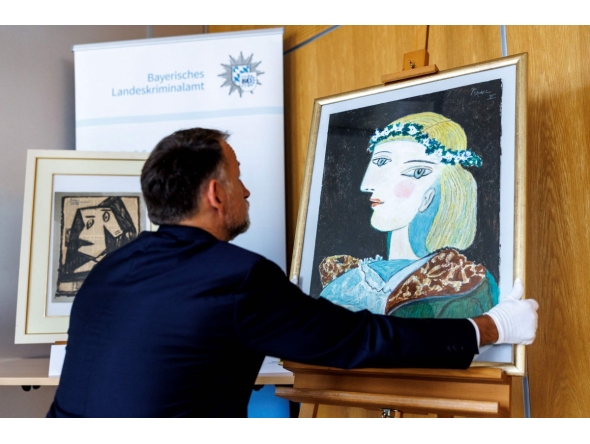 Patrick Haggenmueller, Head of the Art Investigation Unit of the Bavarian State Criminal Police Office (BLKA), displays the forged painting 'Portrait of Marie-Therese Walter with garland', offered as artwork by Spanish artist Pablo Picasso and confiscated by the police, during a presentation in the premises of the Bavarian State Criminal Investigation Department in Munich, southern Germany, on October 24, 2025. Photo by Matthias BALK / AFP
