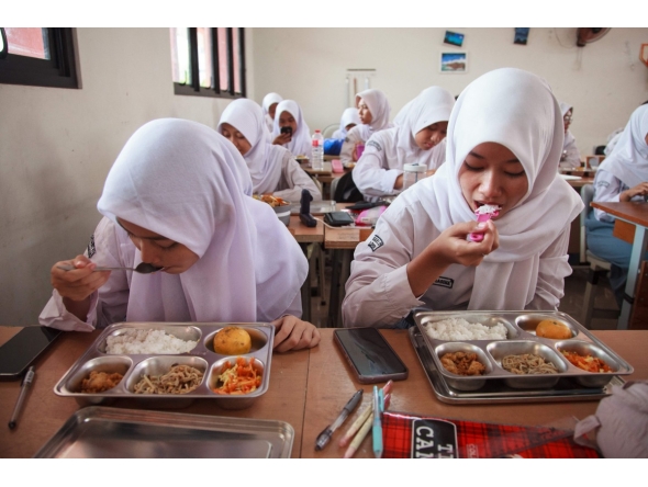 Students eat lunch on the first day of a free-meal program at 11 State Senior High School in East Jakarta on January 6, 2025. Photo by Aditya IRAWAN / AFP

