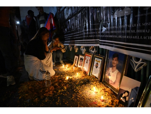 Family members of those killed in September anti-corruption protests take part in a candlelight vigil in front of the fire-damaged parliament building in Kathmandu on November 9, 2025. (Photo by Prakash Mathema / AFP)

