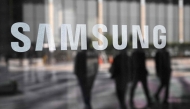 People walk past the Samsung logo displayed on a glass door at the company's Seocho building in Seoul on April 30, 2025. Photo by Jung Yeon-je / AFP