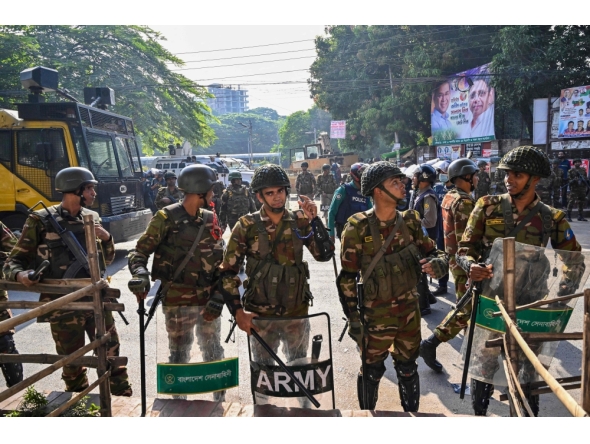 Security personnel stand guard as demonstrators attempt to demolish the residence of Sheikh Mujibur Rahman in Dhaka on November 17, 2025. (Photo by Munir Uz Zaman / AFP)