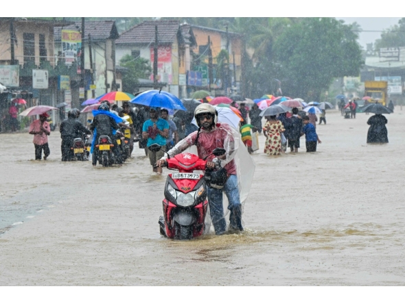 People wade through a flooded road after heavy rainfall in Kaduwela on the outskirts of Colombo on November 28, 2025. (Photo by Ishara S. KODIKARA / AFP)
